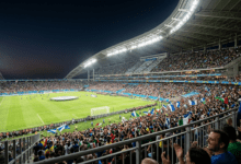 Biggest Sporting Events.A dramatic wide-angle shot of a floodlit stadium under the night sky, packed with cheering fans during a major global championship final.