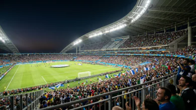 Biggest Sporting Events.A dramatic wide-angle shot of a floodlit stadium under the night sky, packed with cheering fans during a major global championship final.